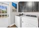 Laundry room with modern appliances, practical cabinets, a door to the outside, and wood-style flooring at 12714 Tyler Run Ave, Odessa, FL 33556