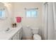 Clean, bright bathroom featuring a white sink, toilet, and shower with white tiles and a colorful pink towel at 139 Adair Ave, Sarasota, FL 34243