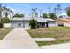 A well-manicured gray house on a lot featuring a long driveway and a cozy covered entryway at 16834 Toledo Blade Blvd, Port Charlotte, FL 33954