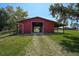 Exterior rear view of the barn featuring its red facade and the surrounding green lawn at 16918 Waterline Rd, Bradenton, FL 34212