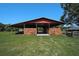 Exterior view of a barn with open stalls and a red roof against a backdrop of a grassy field at 16918 Waterline Rd, Bradenton, FL 34212