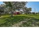 Picturesque red barn nestled among mature trees, offering a classic rural charm on a sprawling green lawn at 16918 Waterline Rd, Bradenton, FL 34212