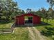 A beautiful aerial view of a bright red barn house with multiple stalls at 16918 Waterline Rd, Bradenton, FL 34212