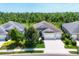 Aerial view of a home's exterior showcasing professional landscaping, three-car garage, and mature tree backdrop at 16943 Rosedown Gln, Parrish, FL 34219
