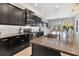 Modern kitchen featuring dark cabinetry, stainless appliances, granite counters, and an open layout at 16943 Rosedown Gln, Parrish, FL 34219