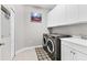 Well-equipped laundry room with modern washer and dryer, and white cabinets at 16943 Rosedown Gln, Parrish, FL 34219
