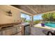 Outdoor kitchen with stainless steel appliances and a beverage cooler, overlooking the waterfront pool area at 203 Robin Dr, Sarasota, FL 34236