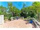 Brick paver patio surrounded by tropical landscaping and a white picket fence at 216 Matisse Cir, Nokomis, FL 34275