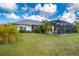 Spacious backyard with lush green lawn and partial view of home and screened in pool at 217 Mariner Ln, Rotonda West, FL 33947