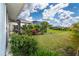 Spacious backyard with green lawn and mature landscaping that surrounds the home with screened lanai at 217 Mariner Ln, Rotonda West, FL 33947