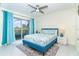 Sunny bedroom featuring sliding glass doors, ceiling fan, white tile floor, and vibrant turquoise accents at 217 Mariner Ln, Rotonda West, FL 33947