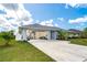 Home featuring a large open garage, well-maintained lawn and landscaping, and blue siding at 217 Mariner Ln, Rotonda West, FL 33947