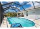 Screened-in pool with lounging and dining space that overlooks landscaping and a bright blue sky at 217 Mariner Ln, Rotonda West, FL 33947