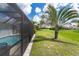 Exterior view of pool and lush backyard with view of screened pool enclosure at 217 Mariner Ln, Rotonda West, FL 33947