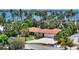 Waterfront home featuring a terracotta roof, lush landscaping, and a view of the ocean lined with palm trees at 223 Seagull Ln, Sarasota, FL 34236