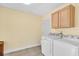 Bright laundry room with tile flooring, upper cabinets, and modern, white, front-loading washer and dryer at 3205 33Rd Street W Ct, Bradenton, FL 34205