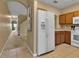 Kitchen featuring tile flooring, modern white refrigerator, wooden cabinets, and an archway entrance at 3707 45Th W Ter # 104, Bradenton, FL 34210