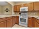 An eat-in kitchen showcasing wooden cabinets, a mosaic backsplash, and white appliances at 3707 45Th W Ter # 104, Bradenton, FL 34210