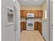 Kitchen featuring tile flooring, oak cabinets, and modern white appliances at 3707 45Th W Ter # 104, Bradenton, FL 34210