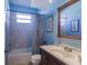 A blue bathroom featuring a tub shower, a window and a single sink vanity at 3835 W Price Blvd, North Port, FL 34286