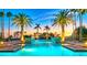 Beautifully lit pool area featuring palm trees, waterfalls, and comfortable lounge chairs at sunset at 435 L Ambiance Dr # Ph-J, Longboat Key, FL 34228