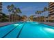 Spacious swimming pool beautifully illuminated at night, complemented by palm trees and lush greenery at 435 L Ambiance Dr # Ph-J, Longboat Key, FL 34228
