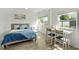 Sun-drenched bedroom with light wood floors, white paneling, large windows, desk and chair set, and beach-themed decor at 4519 Brooksdale Dr, Sarasota, FL 34232