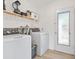 Functional laundry room with modern washer and dryer, storage shelving, and an exterior door for convenience at 4519 Brooksdale Dr, Sarasota, FL 34232