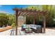 Cozy outdoor seating area under a pergola with string lights and stylish furniture surrounded by lush greenery at 5238 Susan Ave, Sarasota, FL 34231