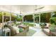 Screened lanai featuring wicker furniture, ceiling fans, and views of a lush backyard with a pool and pergola at 5238 Susan Ave, Sarasota, FL 34231