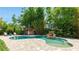 Backyard pool area with waterfall feature, a tiki bar, lounge chairs, mature landscaping, and brick pavers at 5238 Susan Ave, Sarasota, FL 34231