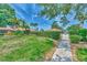 Landscaped walkway and entrance to the community pool with lush greenery, palm trees, and mature trees at 5651 Golf Pointe Dr # 5651, Sarasota, FL 34243