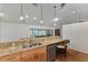 Kitchen bar with wood cabinets, granite countertop, stainless steel sink, and view to billiards room at 5651 Golf Pointe Dr # 5651, Sarasota, FL 34243