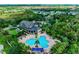Aerial view of a neighborhood clubhouse and a sparkling blue swimming pool surrounded by lush greenery and palm trees at 5735 Bungalow Grove Ct, Palmetto, FL 34221