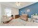 Cozy bedroom with a blue accent wall, crib, and white shelving at 5735 Bungalow Grove Ct, Palmetto, FL 34221