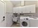 Laundry room with washer, dryer, cabinets, sink, and decorative tiling at 5742 39Th Street E Cir, Bradenton, FL 34203