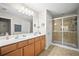 Bathroom featuring double sinks, wood cabinets, framed mirrors, and a glass enclosed shower at 5866 Guarino Dr, Sarasota, FL 34238