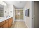Spacious bathroom featuring double sinks, wood cabinets, framed mirrors, and a glass-enclosed shower at 5866 Guarino Dr, Sarasota, FL 34238