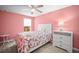 Cozy bedroom featuring pink walls, a ceiling fan, a window, a bed with a floral comforter, and a white dresser at 5866 Guarino Dr, Sarasota, FL 34238