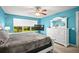 Bright bedroom featuring a ceiling fan, a window overlooking greenery, a white dresser, and vibrant blue walls at 5866 Guarino Dr, Sarasota, FL 34238