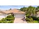 Charming home featuring a tile roof, brick driveway, and well-maintained landscaping with vibrant greenery and a mature palm tree at 5866 Guarino Dr, Sarasota, FL 34238