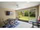 The enclosed lanai features a ceiling fan, outdoor dining set, and a beautiful view of the lush backyard at 5866 Guarino Dr, Sarasota, FL 34238