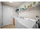 Bright laundry room with white washer, dryer, utility sink, storage shelving, and access door to the garage at 5866 Guarino Dr, Sarasota, FL 34238