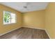 Bright bedroom with wood-look floors, ceiling fan, and large window letting in natural light at 6113 55Th E Ter, Bradenton, FL 34203