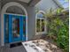 Close up of front entryway with stylish blue door, sidelight windows, and tropical foliage at 6113 55Th E Ter, Bradenton, FL 34203