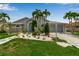 Well-manicured home featuring a lush green lawn, mature palms, and decorative stone landscaping at 6113 55Th E Ter, Bradenton, FL 34203