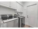 Laundry room with a washing machine and dryer with white cabinets and a door at 6113 55Th E Ter, Bradenton, FL 34203