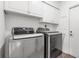 Laundry room with a washing machine and dryer with white cabinets and a door at 6113 55Th E Ter, Bradenton, FL 34203