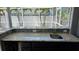 Outdoor kitchen features granite counters with a sink, mosaic tile backsplash and view of the lanai at 6113 55Th E Ter, Bradenton, FL 34203