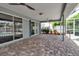 Covered outdoor patio with stone pavers and sliding glass doors leading to a pool at 6113 55Th E Ter, Bradenton, FL 34203